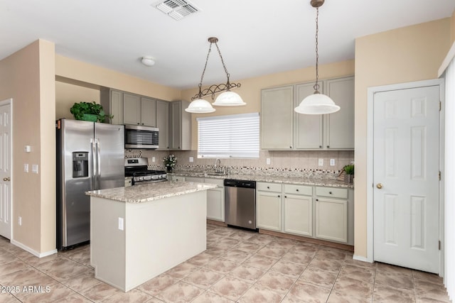 kitchen with stainless steel appliances, hanging light fixtures, a center island, and decorative backsplash