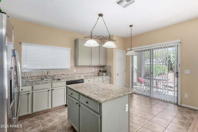 kitchen featuring sink, stainless steel fridge, a center island, tasteful backsplash, and decorative light fixtures