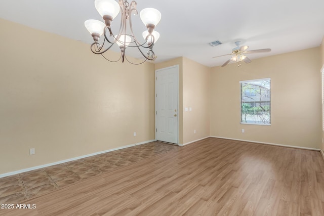 empty room with ceiling fan with notable chandelier and light hardwood / wood-style flooring