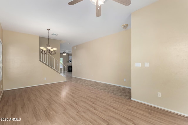 unfurnished living room featuring ceiling fan with notable chandelier and light hardwood / wood-style flooring