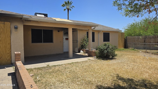 rear view of property featuring roof with shingles, fence, a patio, and stucco siding