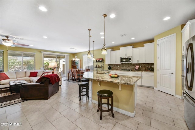 kitchen featuring appliances with stainless steel finishes, a breakfast bar area, pendant lighting, and white cabinetry