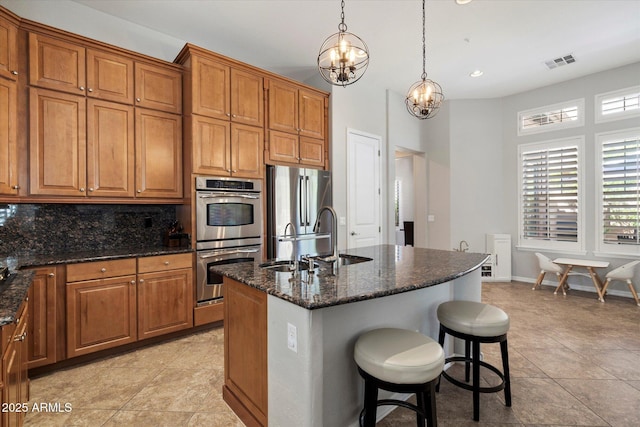 9262 E Desert Park Dr, Scottsdale, AZ 85255 - kitchen featuring appliances with stainless steel finishes, a chandelier, brown cabinets, a center island with sink, and recessed lighting
