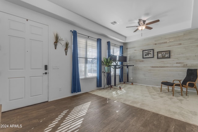 entrance foyer with ceiling fan, wood walls, and dark wood-type flooring