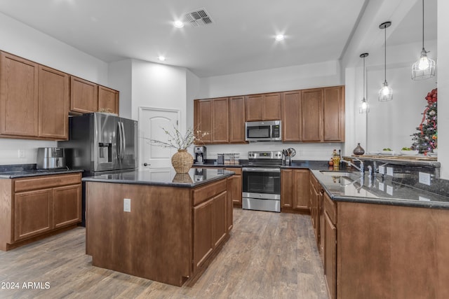 kitchen featuring a center island, sink, dark wood-type flooring, hanging light fixtures, and stainless steel appliances