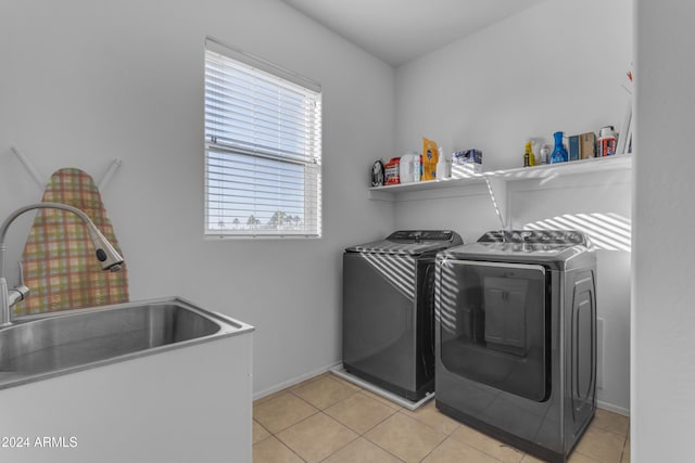 laundry area featuring washer and dryer, light tile patterned flooring, and sink