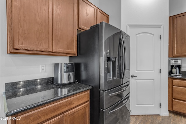 kitchen featuring dark stone counters, stainless steel refrigerator with ice dispenser, and hardwood / wood-style flooring