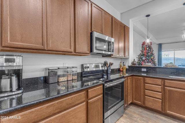 kitchen with pendant lighting, sink, light hardwood / wood-style flooring, dark stone countertops, and appliances with stainless steel finishes