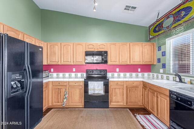 kitchen with tile counters, black appliances, and sink