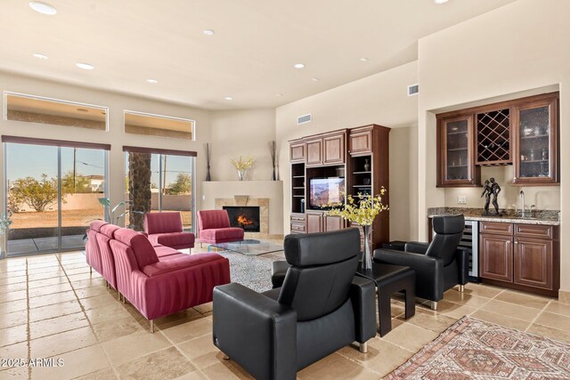 living area with visible vents, recessed lighting, a fireplace, stone tile flooring, and indoor wet bar