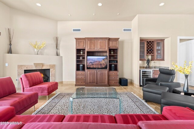 living area with visible vents, beverage cooler, a lit fireplace, recessed lighting, and wet bar