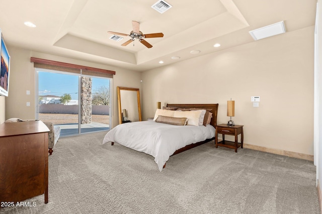 carpeted bedroom with visible vents, a raised ceiling, baseboards, and access to exterior