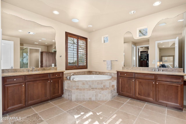 bathroom with a garden tub, two vanities, visible vents, and a sink