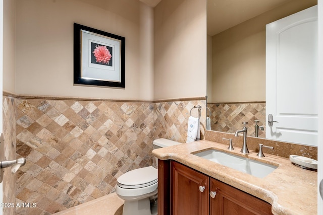 bathroom featuring vanity, tile walls, toilet, and a wainscoted wall