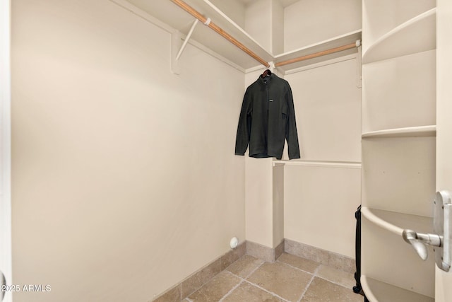 walk in closet with stone tile floors