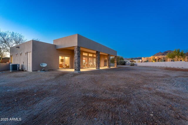 view of front facade featuring a patio, central air condition unit, and stucco siding