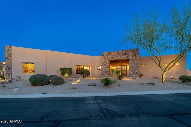 pueblo-style house with stucco siding and stone siding