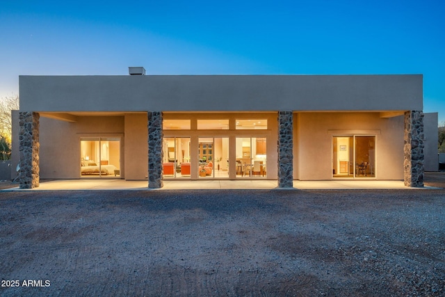 rear view of house with stucco siding and a patio area