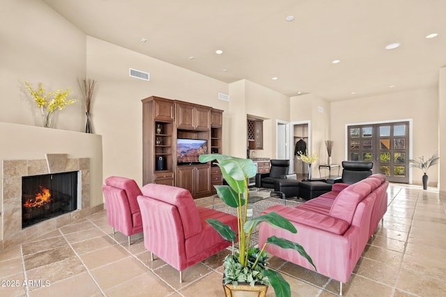 living area featuring a tiled fireplace, recessed lighting, and visible vents