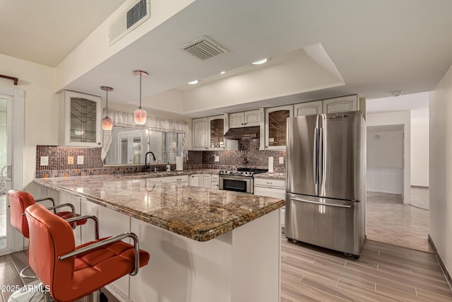 kitchen featuring sink, stainless steel appliances, tasteful backsplash, kitchen peninsula, and pendant lighting