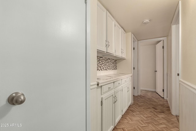 kitchen featuring white cabinets, backsplash, and light parquet floors