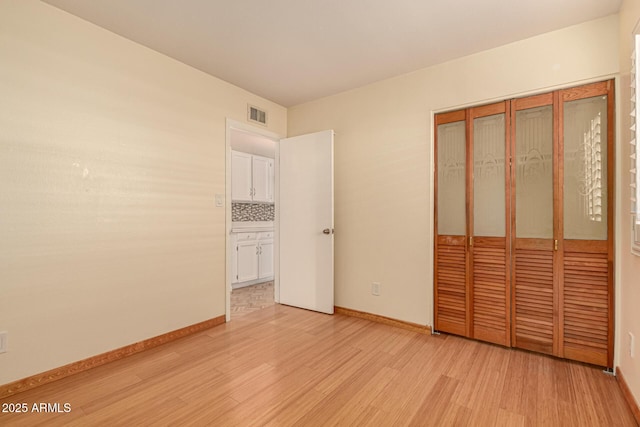 unfurnished bedroom with a closet and light wood-type flooring