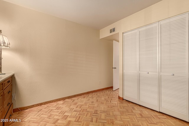 unfurnished bedroom featuring a closet and light parquet floors