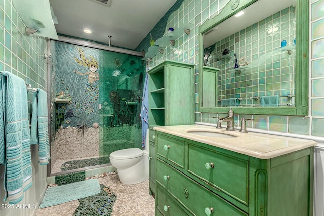 bathroom with a tile shower, vanity, and toilet