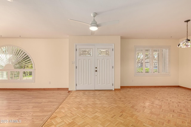 entrance foyer featuring ceiling fan, a wealth of natural light, and light parquet flooring