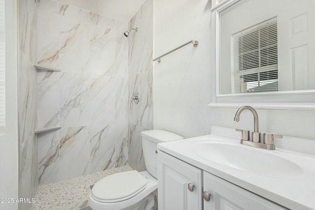 bathroom with toilet, vanity, and tiled shower