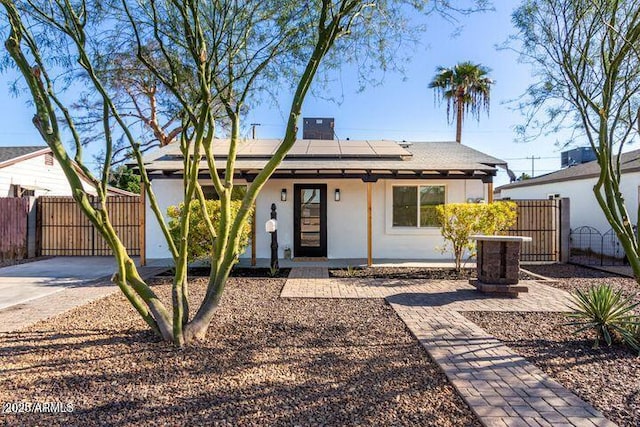 ranch-style home featuring solar panels, a gate, fence, cooling unit, and stucco siding