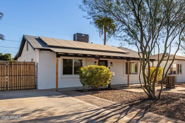 single story home with solar panels, fence, a gate, and stucco siding