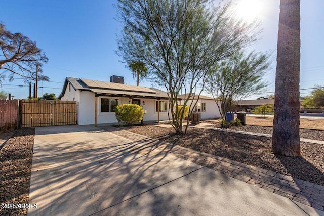 single story home featuring solar panels, fence, a gate, and stucco siding