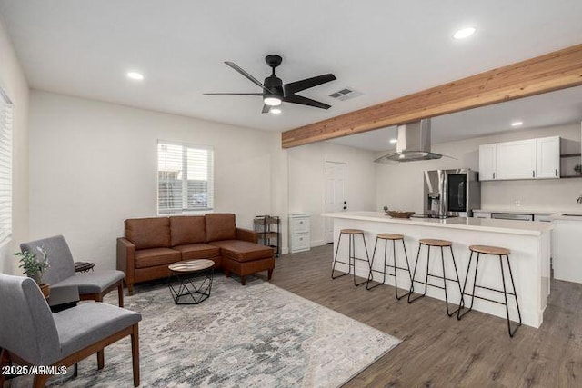 living area featuring beamed ceiling, wood finished floors, visible vents, and recessed lighting