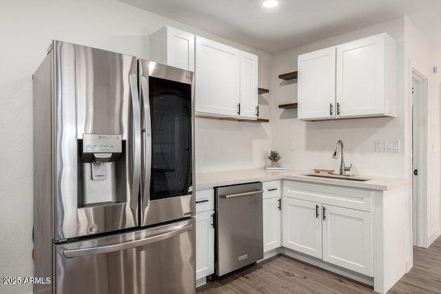 kitchen with white cabinetry, stainless steel appliances, a sink, and wood finished floors