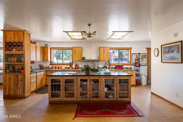 1528 Black Canyon Rd, Heber, AZ 85928 - kitchen with light wood-style flooring, dark countertops, a center island, brown cabinetry, and a textured ceiling