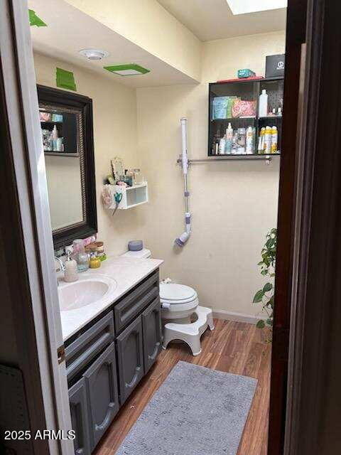 319 E Coronado Rd Unit 1, Phoenix, AZ 85004 - bathroom featuring wood finished floors, vanity, toilet, baseboards, and a skylight
