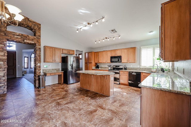 kitchen featuring a kitchen island, light stone counters, black appliances, lofted ceiling, and sink