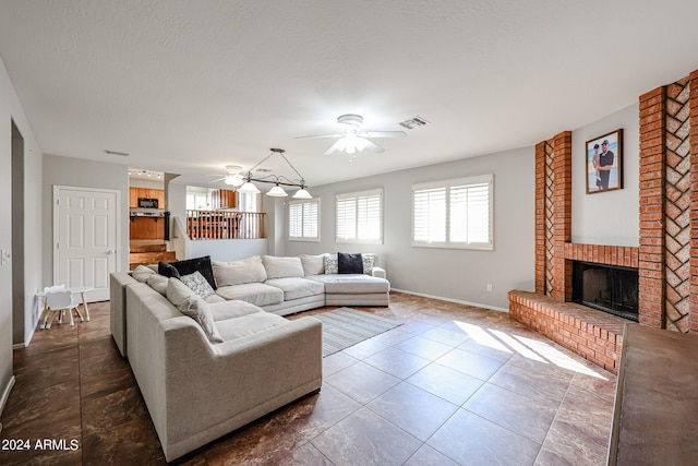 living room featuring a fireplace, dark tile patterned floors, a textured ceiling, and ceiling fan