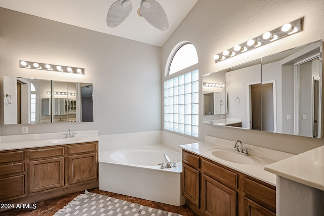 bathroom with ceiling fan, vaulted ceiling, vanity, and a bathing tub