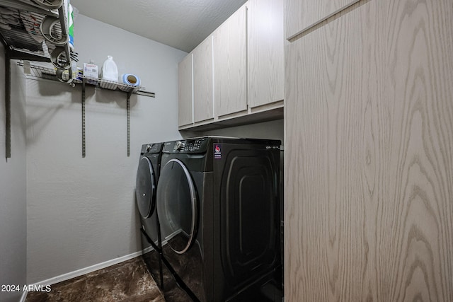 laundry area with a textured ceiling, washer and clothes dryer, and cabinets