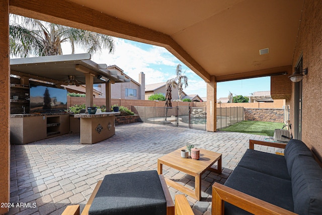 view of patio / terrace featuring ceiling fan, an outdoor living space, and an outdoor kitchen