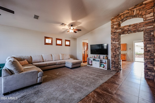 living room with ceiling fan, dark tile patterned flooring, vaulted ceiling, and a textured ceiling