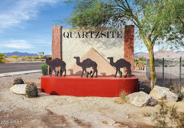 community / neighborhood sign with a mountain view and fence