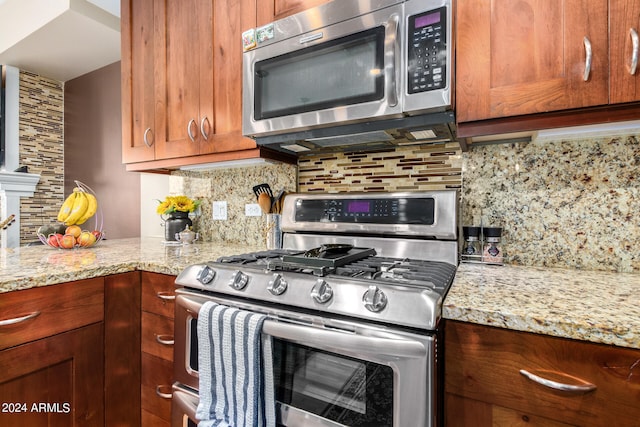 kitchen featuring light stone countertops, decorative backsplash, and stainless steel appliances