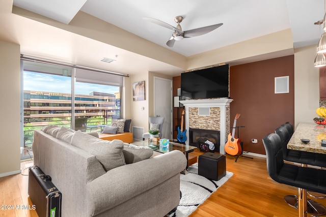 living room with ceiling fan, a fireplace, plenty of natural light, and wood-type flooring