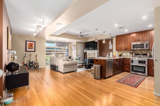 kitchen featuring light hardwood / wood-style flooring, decorative light fixtures, stainless steel appliances, kitchen peninsula, and backsplash