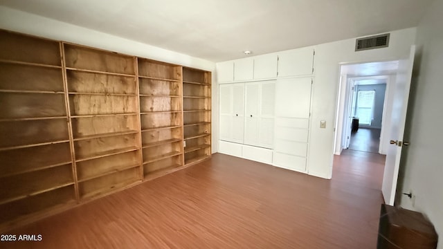 unfurnished bedroom featuring dark wood-type flooring, a closet, and visible vents