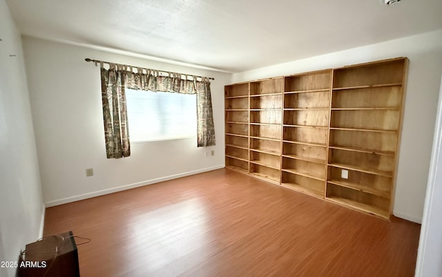 spare room featuring wood finished floors and baseboards