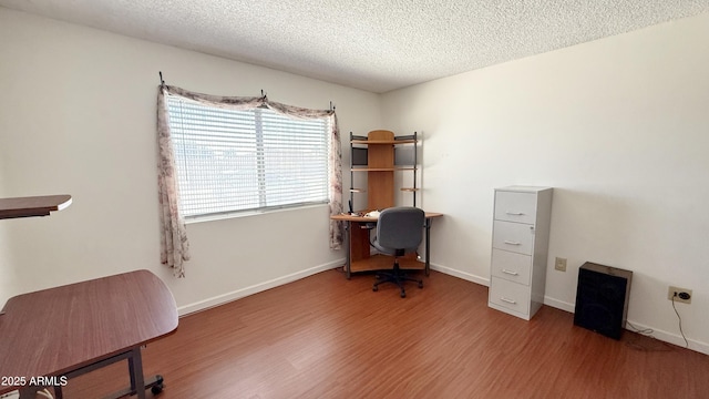 home office with a textured ceiling, baseboards, and wood finished floors